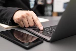 werkproces organiseren in eigen notitieblok genieten van smakelijke cappuccino binnenshuis op een laptopcomputer. werken op bureau met laptop en smartphone. foto