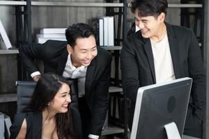 succesvol zakelijk multiage-team dat rond de computer staat voor de presentatie van werk. groep zakenmensen in een vergadering op kantoor, werken op de computer foto