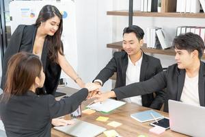 gelukkige zakenmensen op computer vieren succes op het werk zittend in een modern kantoor. succesvolle onderhandelingen. business team kijken naar de computermonitor. foto