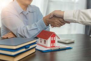 makelaar die de klant de hand schudt na ondertekening van het contract en een zakelijke deal heeft gesloten voor eigendomsoverdracht. man makelaar makelaar makelaar handen schudden van tevreden klanten huiseigenaren foto