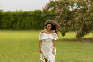 vrolijke jonge vrouw gevangen door de zomerregen in het park foto