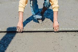 werknemer hij gebruikt een troffel en egaliseert beton op de vloer van het gebouw. Betonplaat gieten foto