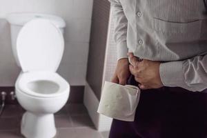 man met weefsel in de buurt van een toiletpot - maaggezondheidsprobleem foto