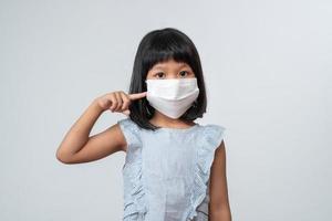 portret van een aziatisch meisje met een beschermend gezichtsmasker klaar voor het nieuwe schooljaar met pandemische beperkingen. concept van kind dat teruggaat naar school en een nieuwe normale levensstijl foto
