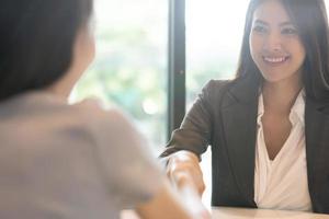 portret jonge Aziatische vrouw interviewer en geïnterviewde handen schudden voor een sollicitatiegesprek .business mensen handdruk in moderne kantoren. groet deal concept foto