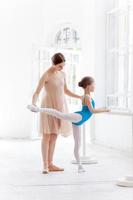 de kleine ballerina poseren bij ballet barre met persoonlijke leraar foto