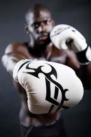jonge atletische bokser die handschoenen op zwarte achtergrond draagt. foto