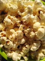 hoog zicht op rijpe popcorn geserveerd in groene bowl.close up. Naast het helpen van je afvallen, heeft het eten van popcorn ook andere gezondheidsvoordelen. foto