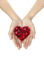 mooie vrouw hand met een rode hartvormige diamant op een witte geïsoleerde achtergrond foto
