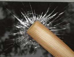 honkbalknuppel slaat door gebroken glas foto