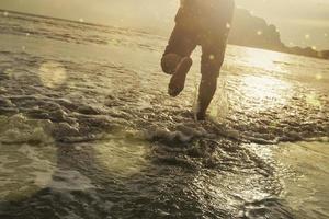 man sprong op het strand bij zonsondergang foto