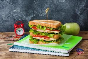 gezonde lunch voor school met sandwich, verse appel. diverse kleurrijke schoolspullen. ruimte kopiëren. foto