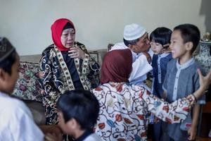 lebaran thuiskomst in de geboorteplaats begroeten elkaar en verontschuldigen zich tijdens de eid. familie omhelzen elkaar, grootouders met kleinkinderen. familiebijeenkomst concept. foto