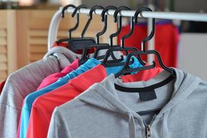 kleurrijke sportshirts en jassen die aan een kledingrek hangen in een modewinkel