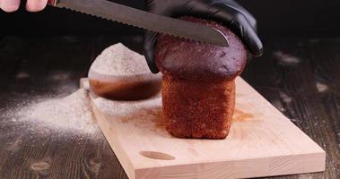 een rechthoekig brood donker roggebrood wordt in stukjes gesneden foto