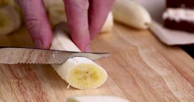 een rijpe gele banaan in stukjes snijden tijdens het koken foto