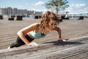 gezonde levensstijl. coach oefeningen op straat. een zelfverzekerde vrouw doet een training. een atleet in comfortabele sportkleding. buitenfitness in de stad. foto