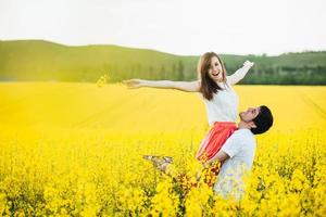 romantische man voedt zijn vriendin op, geniet van saamhorigheid op een prachtig geel veld, poseert buiten, heeft plezier, lacht vrolijk. verliefde paar brengen zomervakantie door in de natuur. mensen en harmonie concept foto