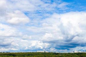 lage grote witte wolken in blauwe lucht boven stadspark foto