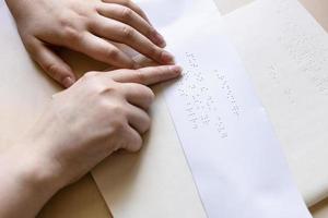 vrouw leest notitie in braille op vel papier foto