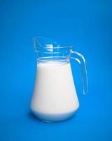 een liter melk in een glazen kan op een blauwe achtergrond foto