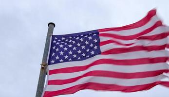Amerikaanse vlag aan een vlaggenmast die langzaam in de wind tegen de lucht beweegt foto