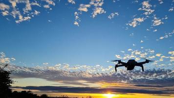 een drone vliegt bij een prachtige en kleurrijke zonsondergang met wolken aan de hemel foto