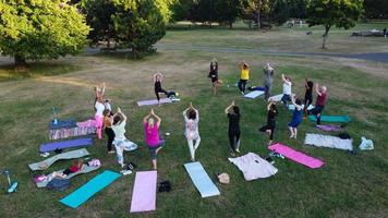 groep vrouwen die samen yoga uitoefenen in het openbare park bij zonsondergang van de hete zomer, luchtfoto hoge hoekmening van wardown park luton engeland uk foto