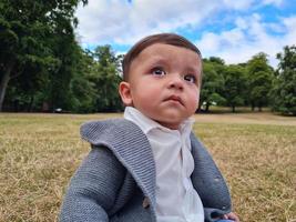 schattige kleine baby baby poseert in een plaatselijk openbaar park in de stad Luton in Engeland foto