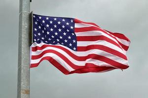 Amerikaanse vlag aan een vlaggenmast die langzaam in de wind tegen de lucht beweegt foto