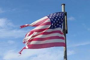 Amerikaanse vlag aan een vlaggenmast die langzaam in de wind tegen de lucht beweegt foto