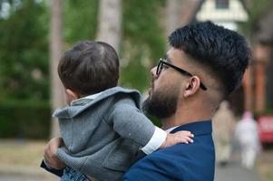Aziatische Pakistaanse vader houdt zijn 11 maanden oude baby vast in het plaatselijke park foto