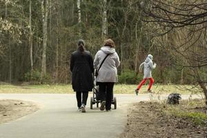 vrouw loopt met kinderwagen voor kind in park. vrouw in de stad. foto