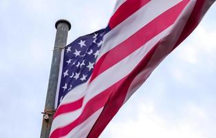 Amerikaanse vlag aan een vlaggenmast die langzaam in de wind tegen de lucht beweegt foto