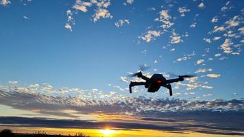 een drone vliegt bij een prachtige en kleurrijke zonsondergang met wolken aan de hemel foto