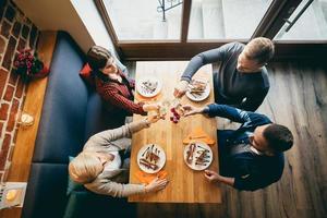 vier vrienden roosteren in een restaurant. bovenaanzicht. foto