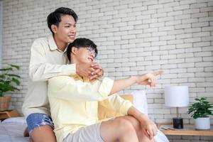 gelukkig aziatisch homopaar ontspannen thuis op de bank, lgbtq-concept. foto