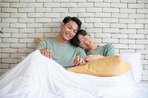 gelukkig aziatisch homopaar hand in hand samen ontspannen thuis op bed, lgbtq-concept. foto