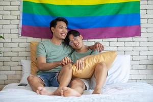 gelukkig aziatisch homopaar hand in hand samen ontspannen thuis op bed, lgbtq-concept. foto