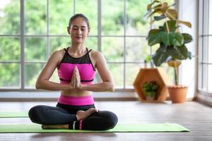 jonge aziatische vrouw die thuis aan yoga werkt en yoga doet, gezond concept. foto