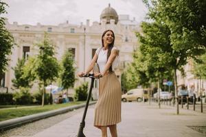 jonge vrouw rijdt op een elektrische scooter op straat foto