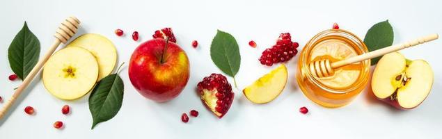 fijne rosj hasjana. traditionele joodse vakantie nieuwjaar. appels, granaatappels en honing op een witte achtergrond. bannerformaat, plaats voor tekst. foto