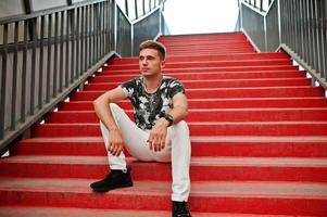 levensstijl portret van knappe man poseren in rode trappen van de stad tonel. foto