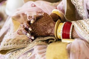 mooie indische bruid die rode armbanden en gouden juwelen draagt. mehndi of henna-ontwerp op handen. nieuwe Indiase bruid op bruiloft.