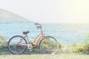 oranje fiets met de achtergrond van de bergen en de zee met warme zon. foto