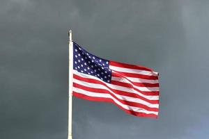 Amerikaanse vlag aan een vlaggenmast die langzaam in de wind tegen de lucht beweegt foto