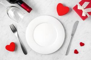 bord met servies, lint, cadeau en rozen voor Valentijnsdag speciaal maaltijdconcept. foto