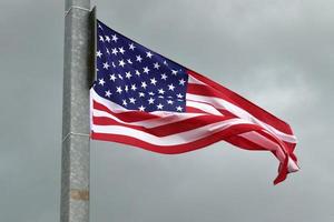 Amerikaanse vlag aan een vlaggenmast die langzaam in de wind tegen de lucht beweegt foto