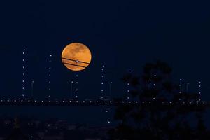 super blauwe bloedmaan achter de Bosporusbrug in Istanbul, Turkije foto