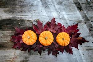 feestelijk herfstdecor van pompoenen, dennen en bladeren op een houten ondergrond. concept van thanksgiving day of halloween. plat lag herfstcompositie met kopieerruimte. foto